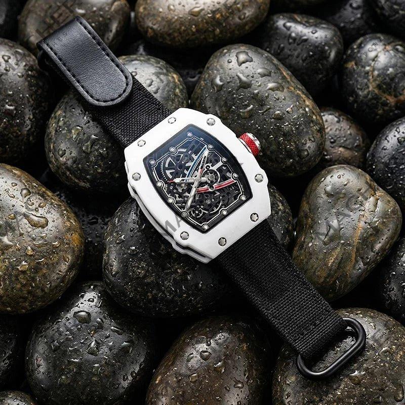 Luxury sport watch with skeleton dial, carbon fiber case, and black strap on wet stones — motorsport-inspired design