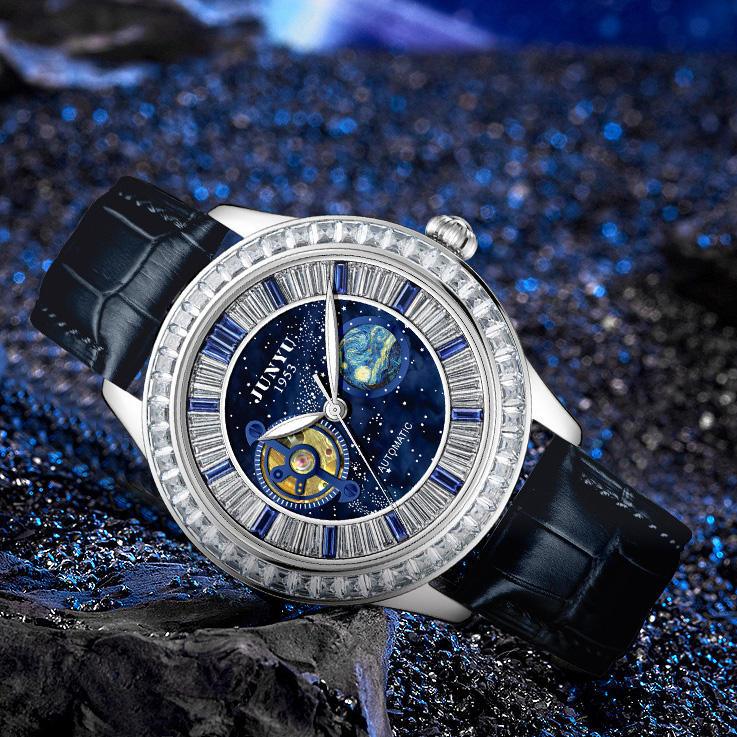 Luxury sport-style watch with blue galaxy dial, gemstone bezel, and black leather strap