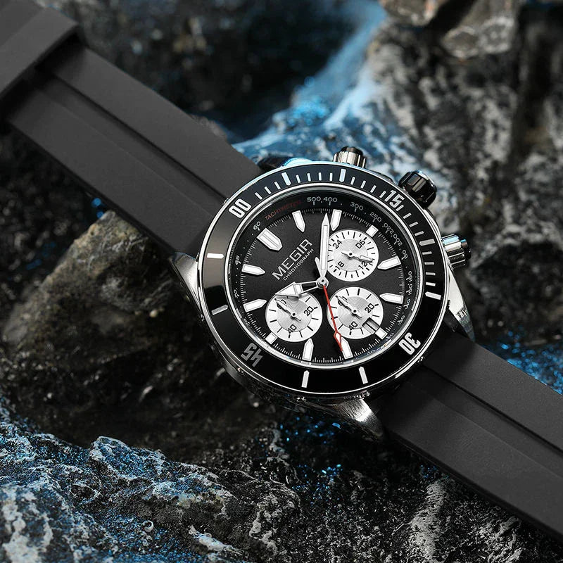 Luxury motorsport-inspired chronograph watch with black bezel and rubber strap on dark rocks