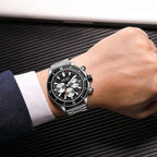 Luxury sport-luxury chronograph watch with black dial, silver subdials, and metal bracelet on wrist