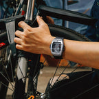 Luxury motorsport-inspired chronograph watch with skeleton dial worn while holding a bicycle
