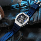 Motorsport-inspired skeleton dial watch with blue rubber strap on black leather background